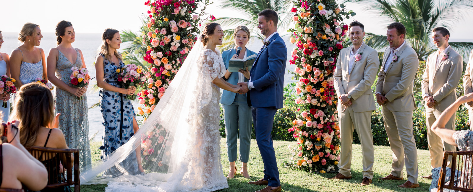 Bride and Groom getting married in front of a large colorful floral arch at their destination wedding in mexico
