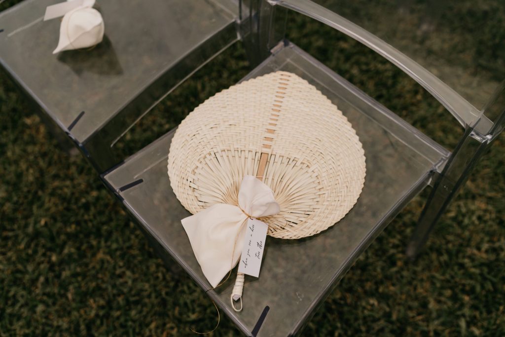 natural fiber fans were at each acrylic chair for the all-white wedding ceremony