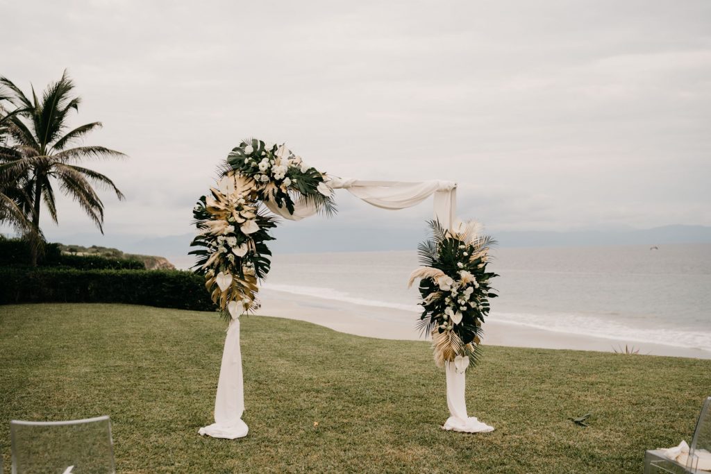 floral installment with white drapery served as the arch for the all-white wedding ceremony