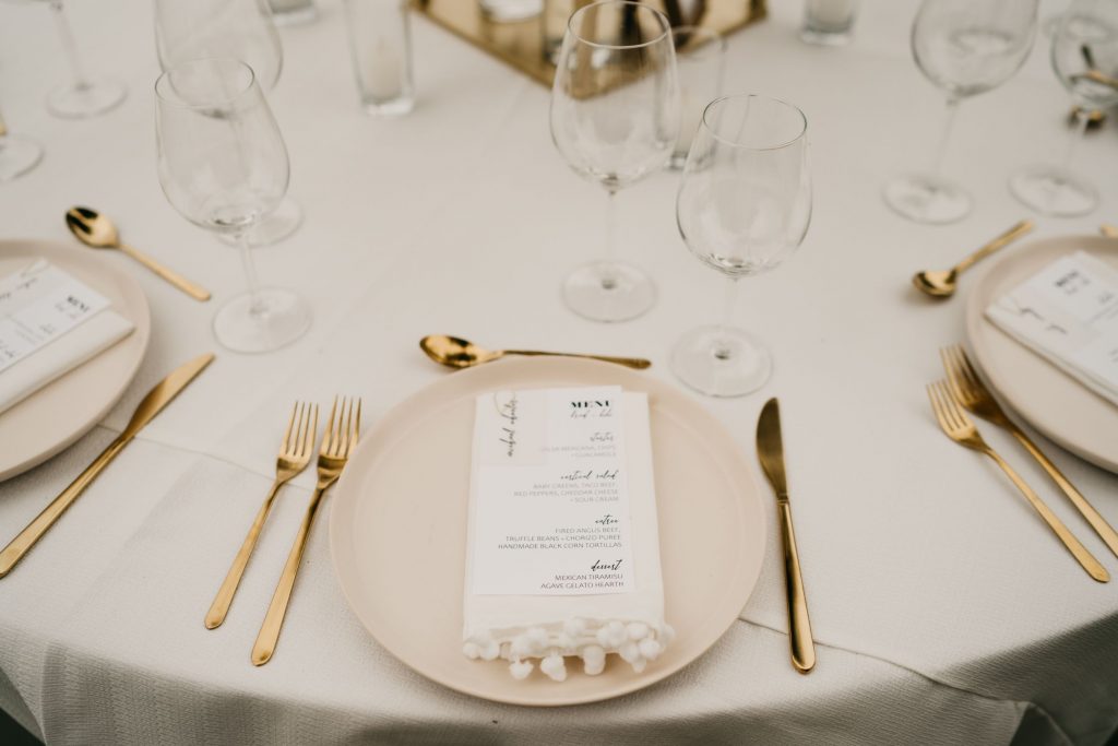 Menus sat on each neutral blate next to gold silverware and crystal glassware