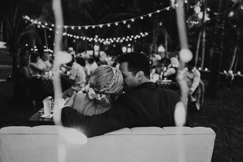 Emily and Bryce steal a kiss during dinner while their guests wine and dine at this Sayulita Mexico destination wedding 